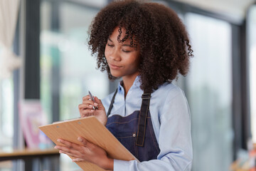 Young Female manager in restaurant with notebook. Woman coffee shop owner with open sign. Small business concept