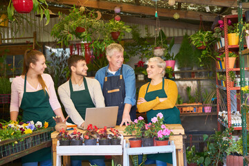 Obraz premium Satisfied gardeners team in the flower shop of the nursery