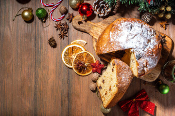 Traditional Christmas panettone cake with dried fruits, spices, Christmas tree and decoration on rustic wooden background 