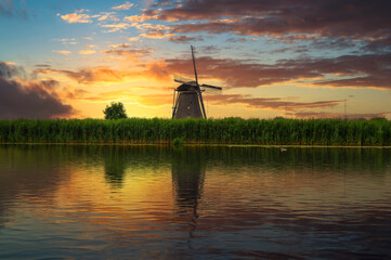 Sunset over an old dutch windmill by a river in Kinderdijk, Netherlands