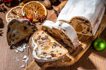 Traditional Christmas Dresdner stollencake with dried fruits, spices, Christmas tree and decoration on rustic wooden background