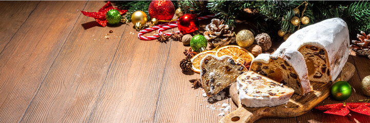 Traditional Christmas Dresdner stollencake with dried fruits, spices, Christmas tree and decoration on rustic wooden background