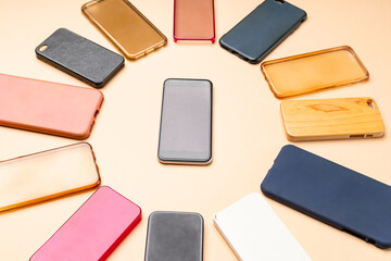 Choice of multicolored plastic back covers for mobile phones on neutral background with a smart phone on the side