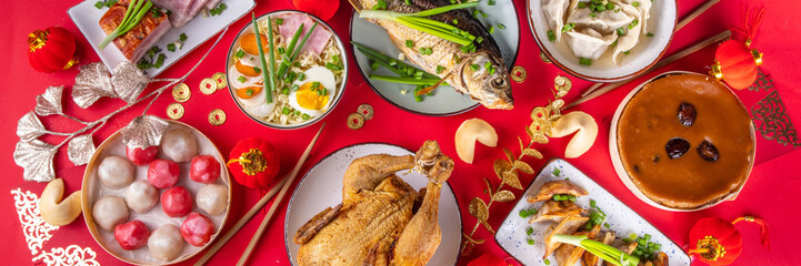 Traditional Chinese lunar New Year dinner table, party invitation, menu background with pork, fried fish, chicken, rice balls, dumplings, fortune cookie, nian gao cake, noodles, chinese decorations