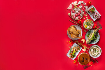 Traditional Chinese lunar New Year dinner table, party invitation, menu background with pork, fried fish, chicken, rice balls, dumplings, fortune cookie, nian gao cake, noodles, chinese decorations