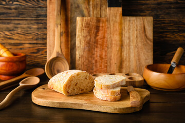 Kitchen utensils with fresh bread on dark wooden background