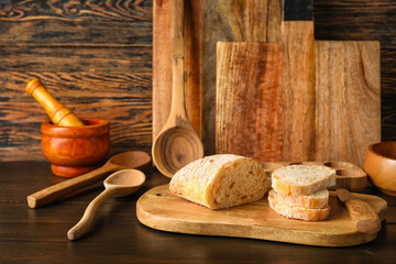 Fototapeta na wymiar Kitchen utensils with fresh bread on dark wooden background