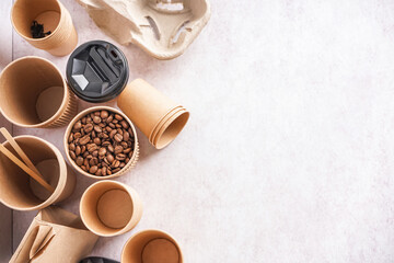 Different paper cups and coffee beans on light background