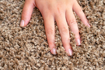 Close up of hand touching soft carpet. Gentle and fluffy carpet between fingers.