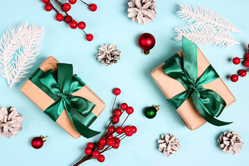 Gift boxes with green ribbons, berries and Christmas decorations on a blue background.