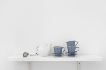 Fototapeta na wymiar Tea set on shelf near light wall