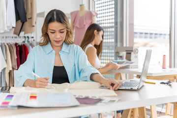 Obraz premium Two Asian women working together Small business, SME, tailoring designs for customers. Both of them acted as great designers.