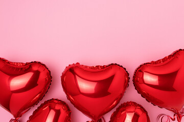 Frame made of red inflatable foil balloons in a heart shape. Concept on a pink background with copy space.