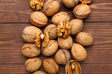 Whole and peeled walnuts on wooden background, closeup