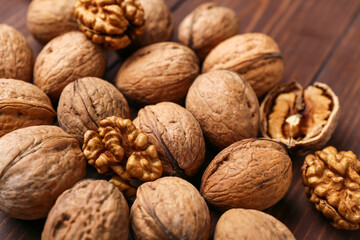 Whole and peeled walnuts on wooden background, closeup