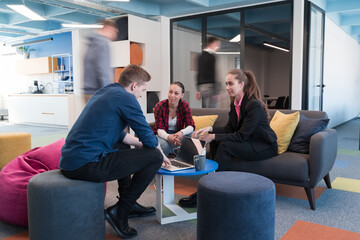 Naklejka premium Multiethnic startup business team on meeting in a modern bright open space coworking office. Brainstorming, working on laptop. Group of coworkers walking around in motion blur.