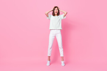 Full length photo of optimistic impressed girl wear striped t-shirt white pants shoes arms on head yell isolated on pink color background