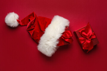 Obraz na płótnie Canvas Santa hat and Christmas gifts on color background