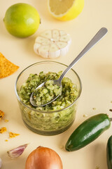 Glass bowl of tasty green salsa sauce on color background