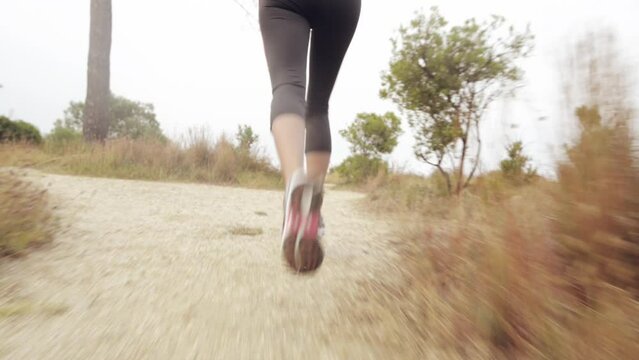 Fitness, exercise and shoes of woman running outdoor on a nature trail with energy, speed and agile body on a mountain dirt road. Athlete runner feet doing workout, training and cardio for health