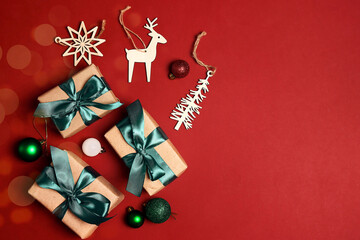 Gift boxes with green ribbons and Christmas decorations on a red background.