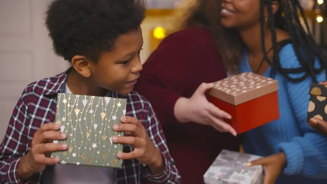 African-American boy opening christmas present box at party