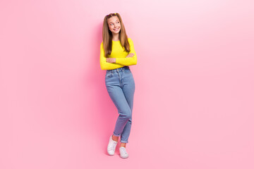 Full length photo of dreamy sweet schoolgirl wear yellow crop top looking empty space arms folded isolated pink color background