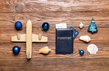 Passport with toy airplane, Christmas decor and seashells on wooden background