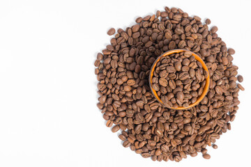 A small saucer with coffee beans stands on a pile of coffee on a white background.