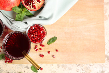 Wooden board with glass of fresh pomegranate juice on color background