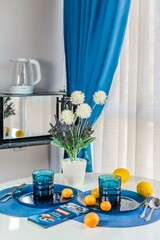 a joyful and cozy setting for a summer breakfast in the kitchen is a white table and blue dishes empty plates and fruits
