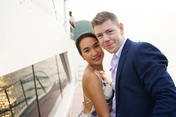Happy Asian and caucasian couple dating on a yacht together. 