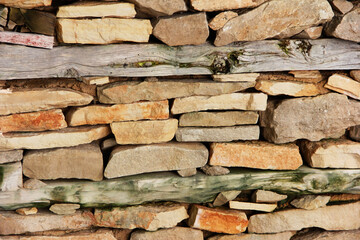 street wall made of natural brown granite stone and dry wooden boards