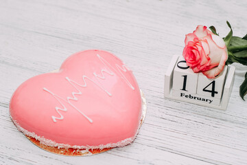 Pink tea rose with heart shaped pink mousse cake and February 14 calendar.