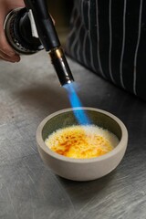 Chef using a kitchen torch for making creme brulee