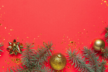 Composition with fir branches and Christmas decorations on red background