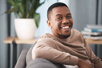 Face, smile and portrait of a black man relax in a living room at a house on a holiday, break or...
