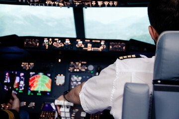 Right hand pilot second officer seated in the flight deck, back view, aircraft cabine © vladdeep