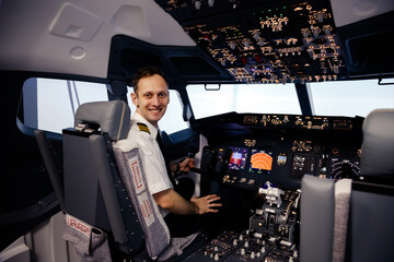 Pilot in cockpit. Rear view of confident male pilot looking over shoulder and smiling while sitting in cockpit © vladdeep