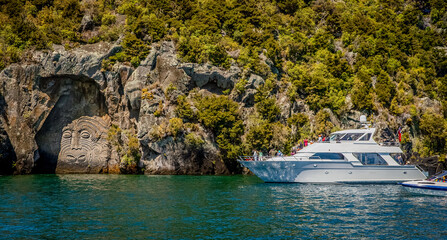 tourist boat with tourists watching traditional rock carving lake taupo north island new zealand. High quality photo