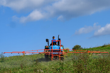 A tractor with a tank and attached equipment for spraying the field from pests and weeds, the process of processing the field.