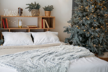 Interior of bedroom with Christmas tree and glowing lights