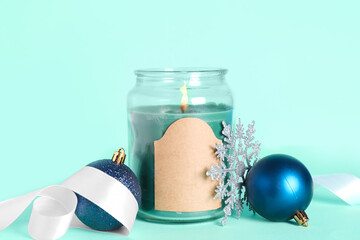 Jar with burning candle, ribbon, snowflake and Christmas balls on color background