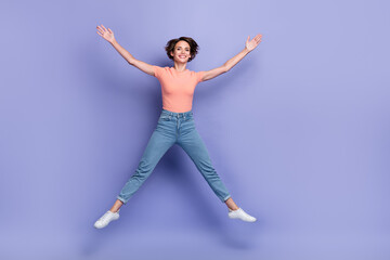 Obraz premium Full length photo of shiny charming girl dressed orange t-shirt jumping high like star empty space isolated purple color background