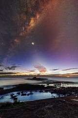 Starry night sky just before sunrise of coastal landscape