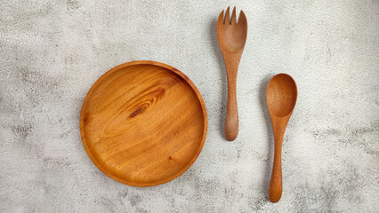 Empty round wooden plate and cutlery isolated on wood textured background