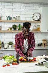 African young man is preparing vegetable salad in the kitchen. Healthy Food. Vegan Salad.