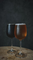 Light and dark cold beer in glasses with water drops. Two craft beers close-up isolated on a dark background.