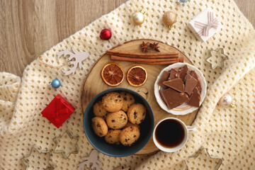 Various Christmas decorations, cup of tea or coffee, sweets, small presents, knitted blanket and candles. Flat lay.