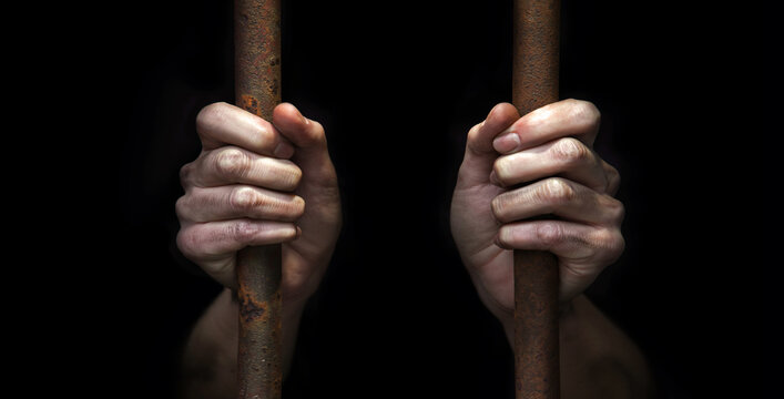The prisoner's hands are holding on to the iron bars
